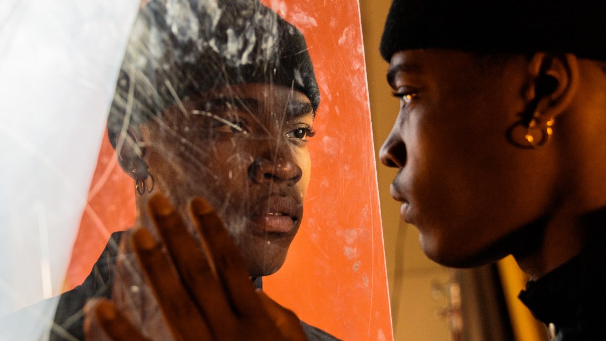 man with a beanie staring at a broken mirror