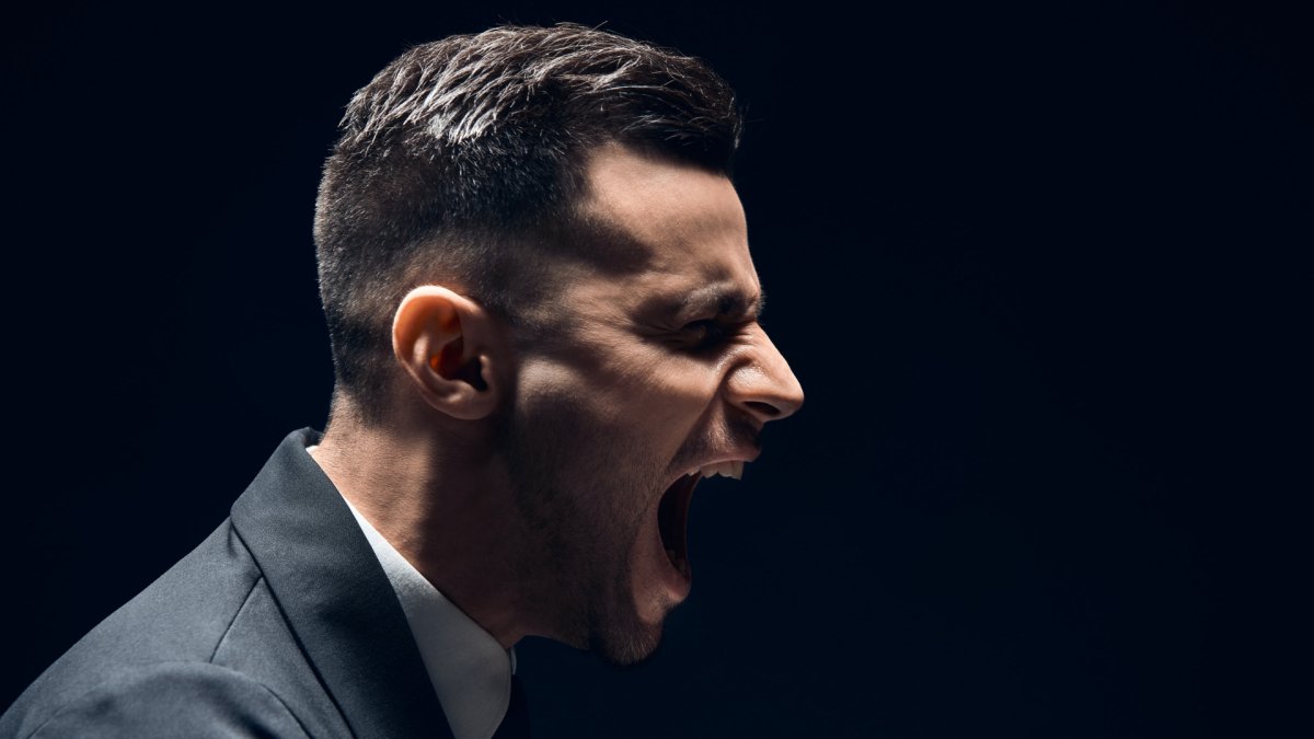 man wearing a suit, seen sideways, screaming, with black background