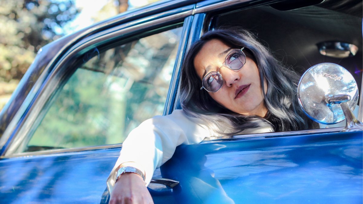 impatient woman inside car leaning out the window and looking up