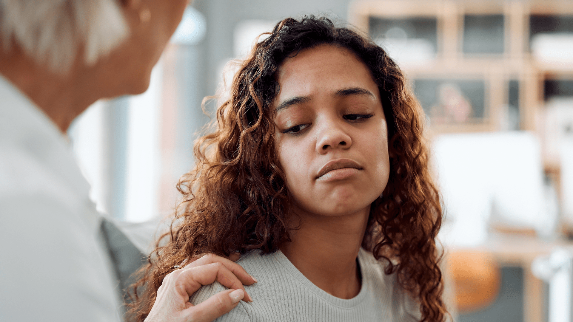woman looking down depressed sad being comforted