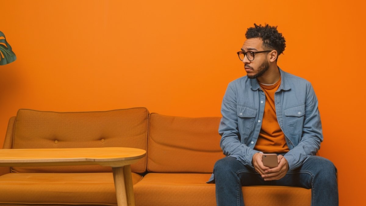 A man sitting on one side of Sofa looking sad missing his partner following No contact Rule