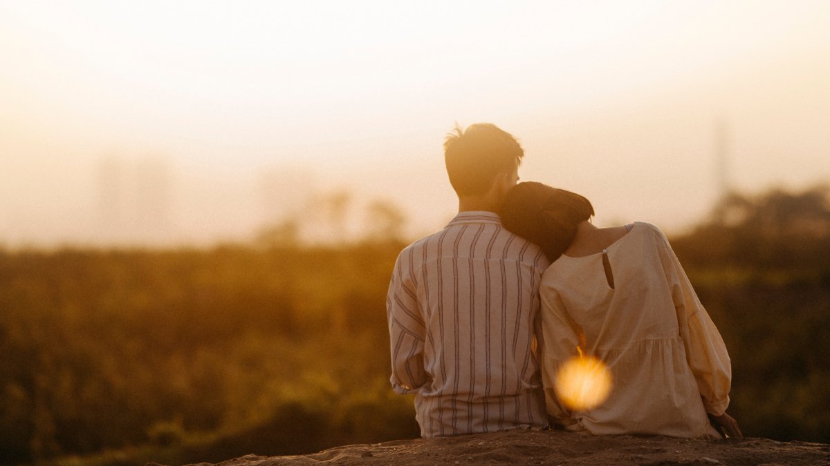 a couple watching sunset, with the woman's head leaning on the man's shoulder