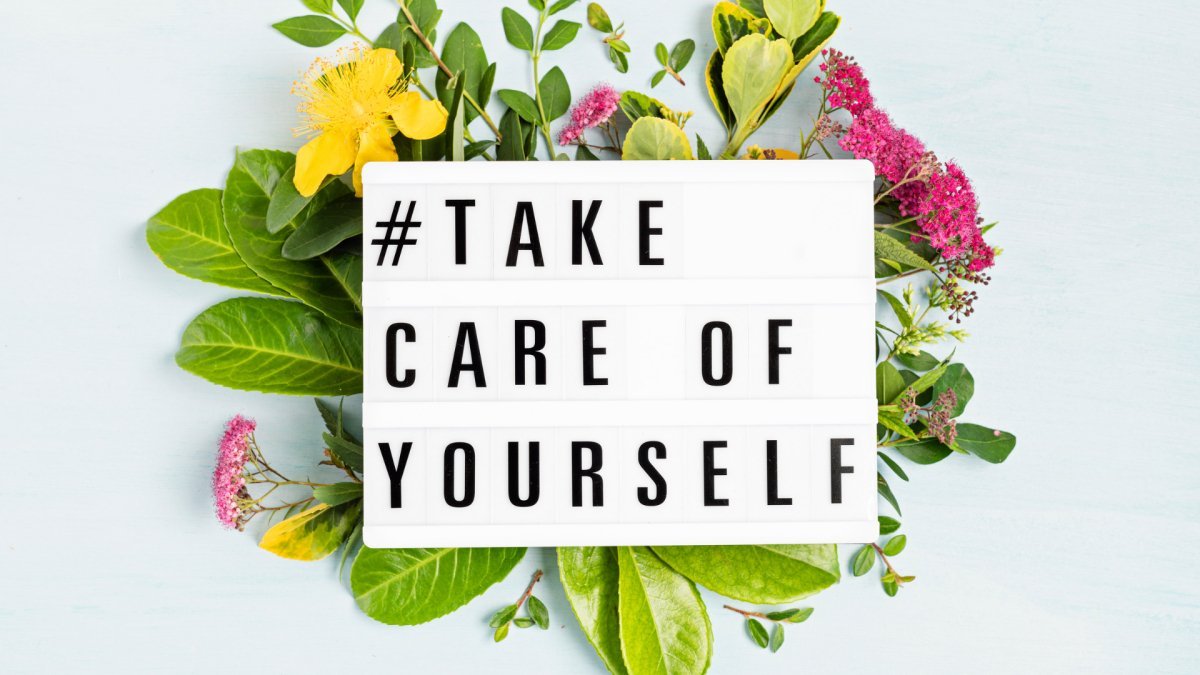 black capital letter saying "#take care of yourself#" with flowers in the background