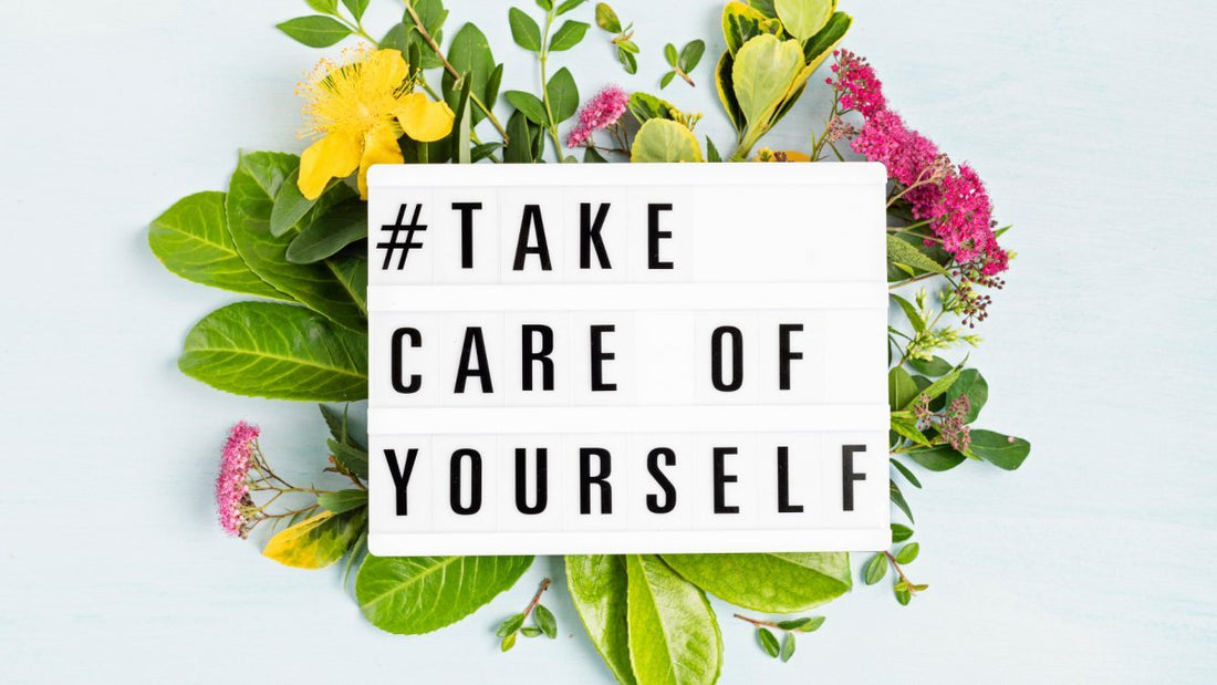 black capital letter saying "#take care of yourself#" with flowers in the background