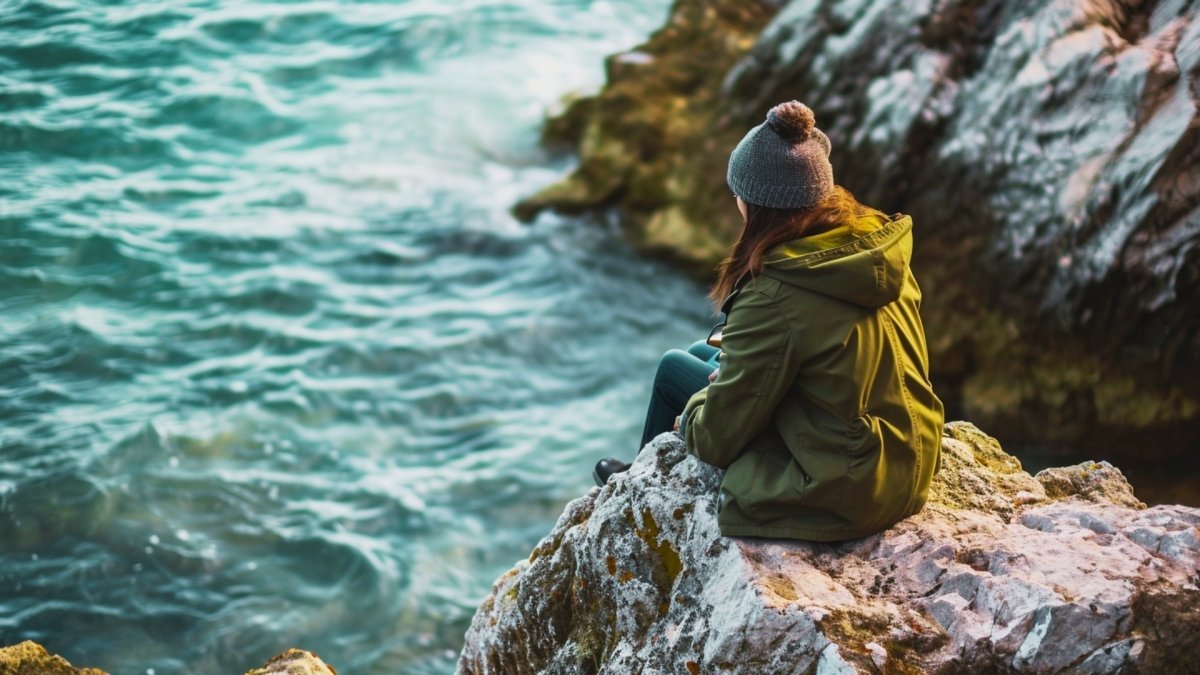 Girl sitting on the rock at the sea side rediscovering herself