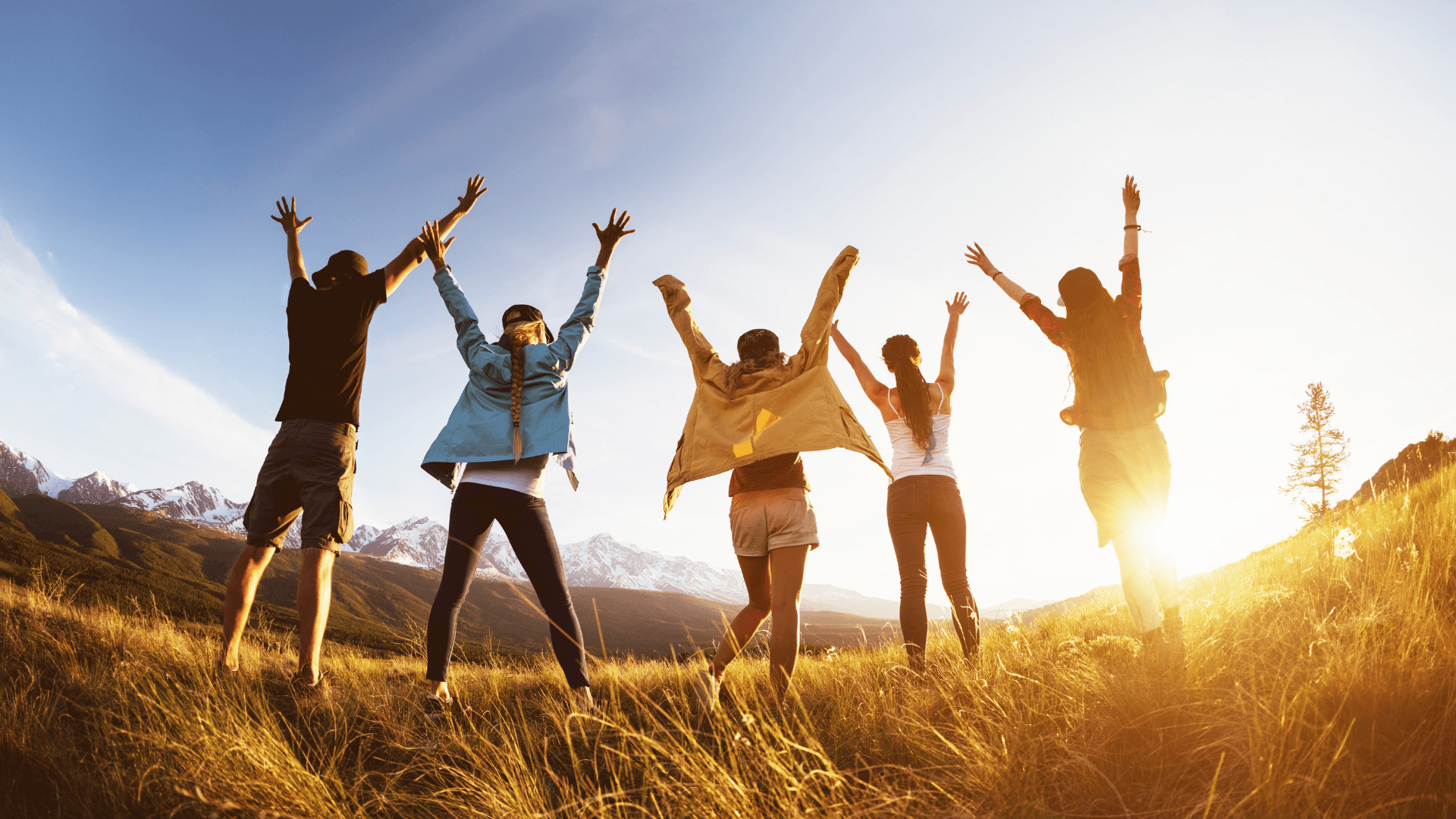 group of five friends jumping hands in the air, sharing happiness with sunset view