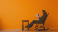 A man sitting on a rocking chair reading Positive thoughts in newspaper on a Sunday morning