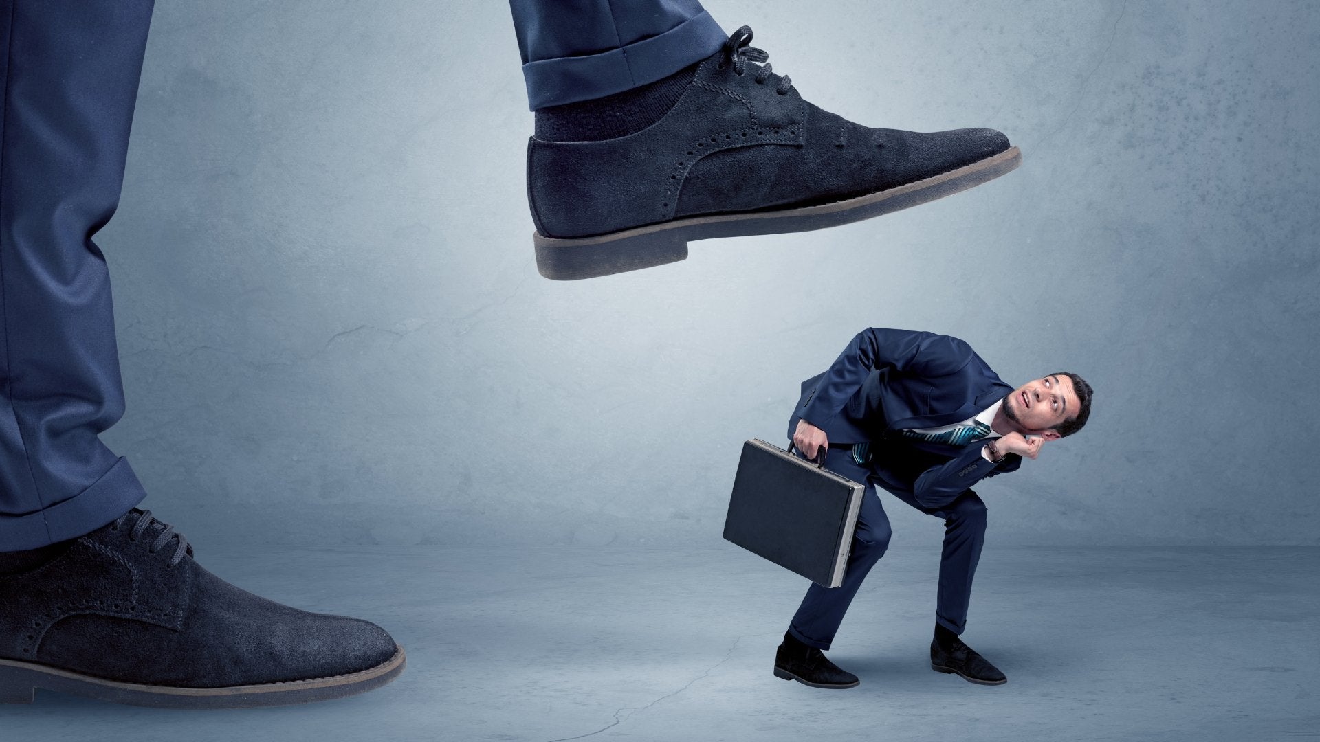 man fearful being stepped on by a massive shoe
