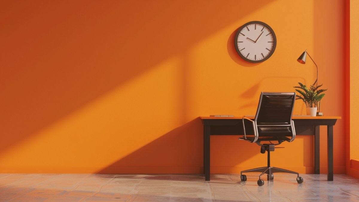A desk and a chair kept in a room with a clock in the wall, ready for Monday morning work