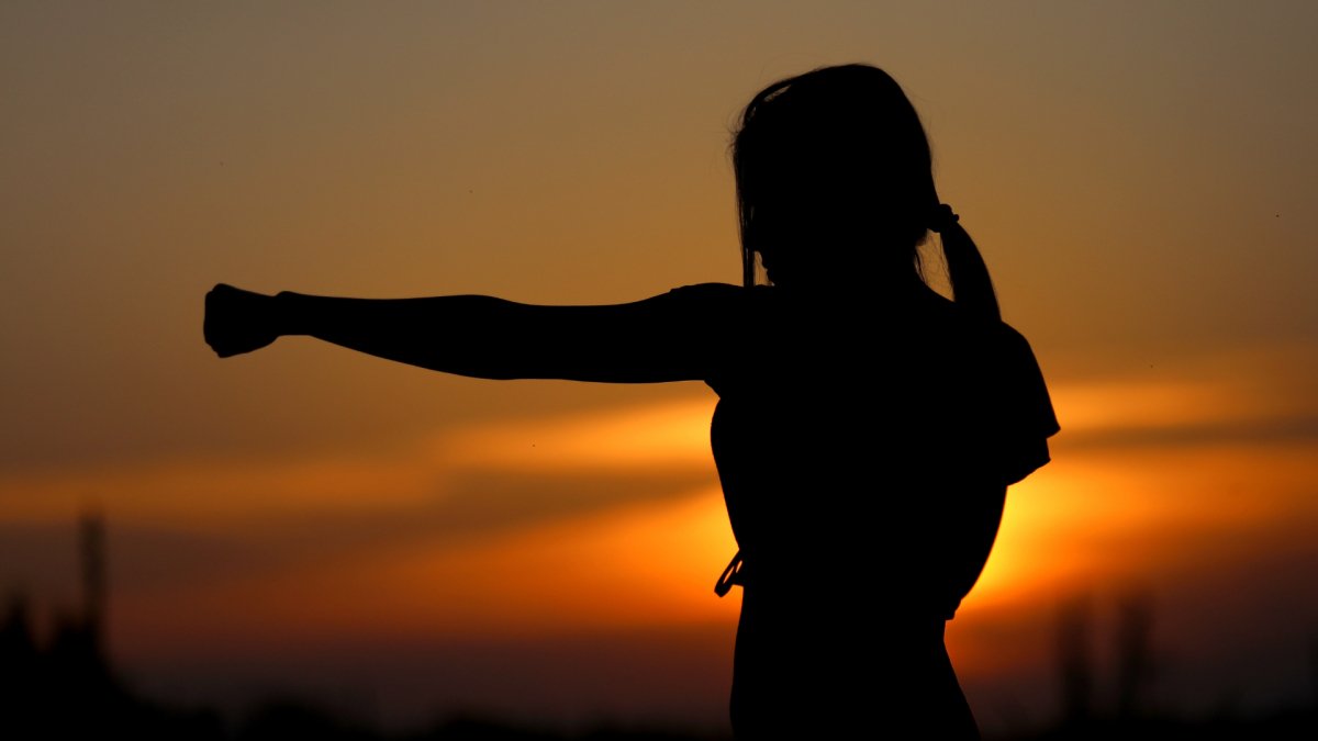 woman at sunset with arm extended showing strength and resilience