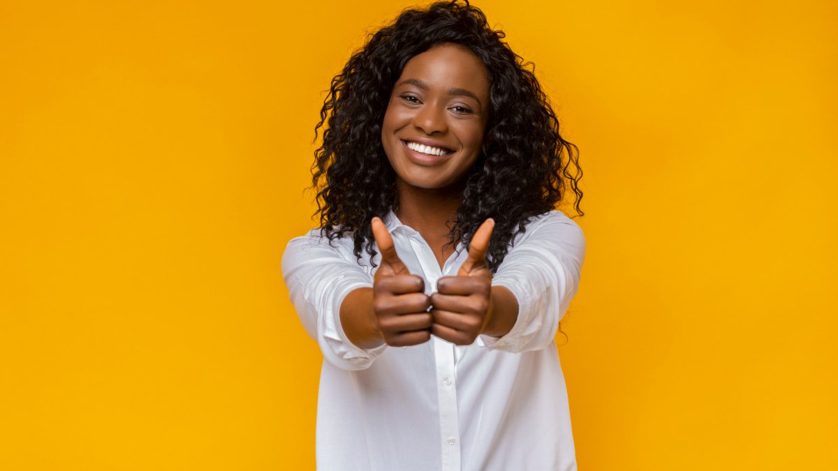 woman with both thumbs up, orange background