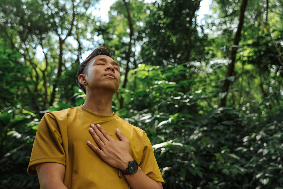 Bayu coach at Life Architekture, wearing yellow t-shirt, eyes closed, hand on heart, in jungle background